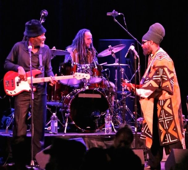 Reggaeband spelar live med bas, trummor och gitarr på en scen